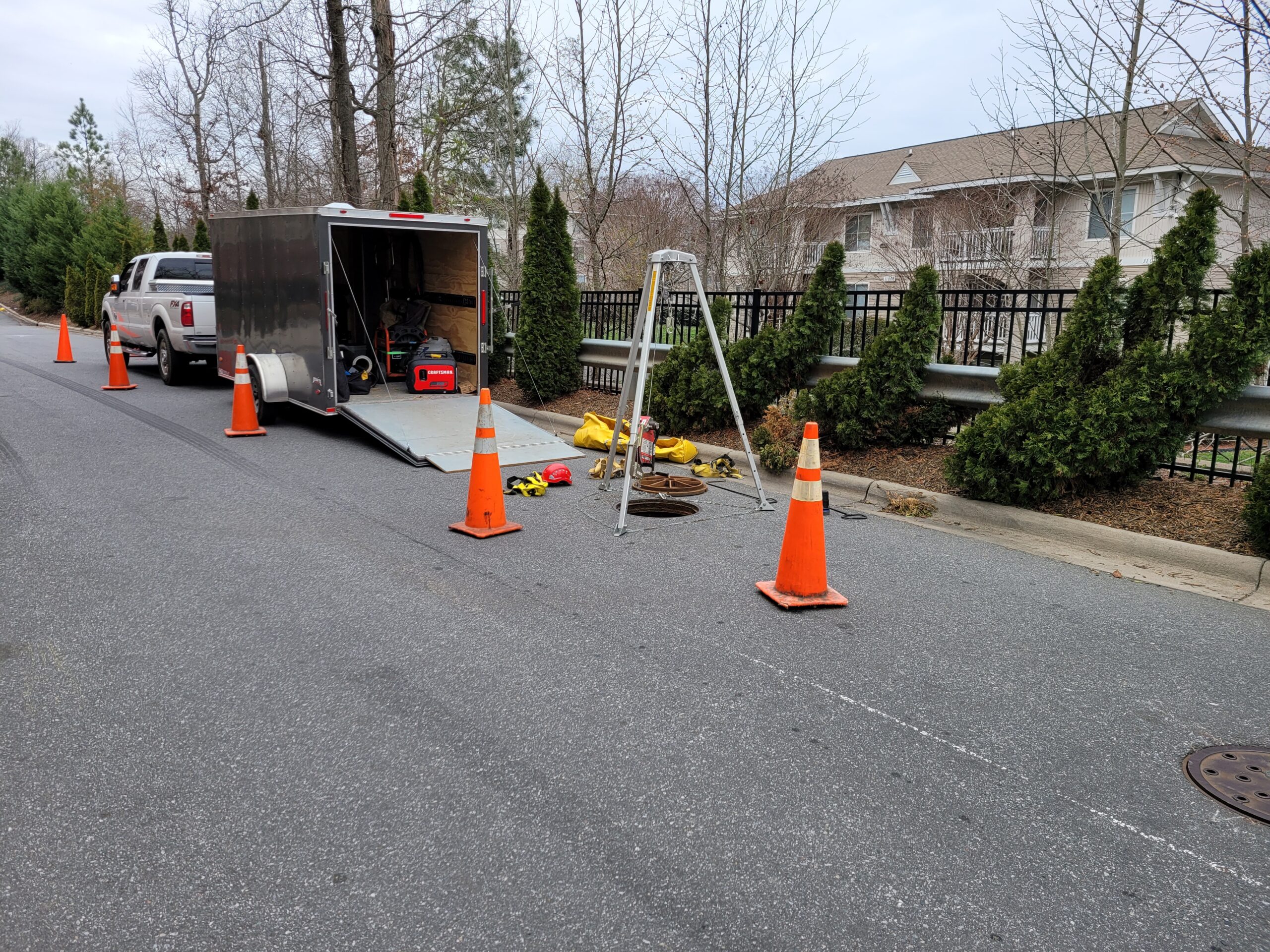 Certified confined space entry team inspecting underground stormwater structure with safety equipment