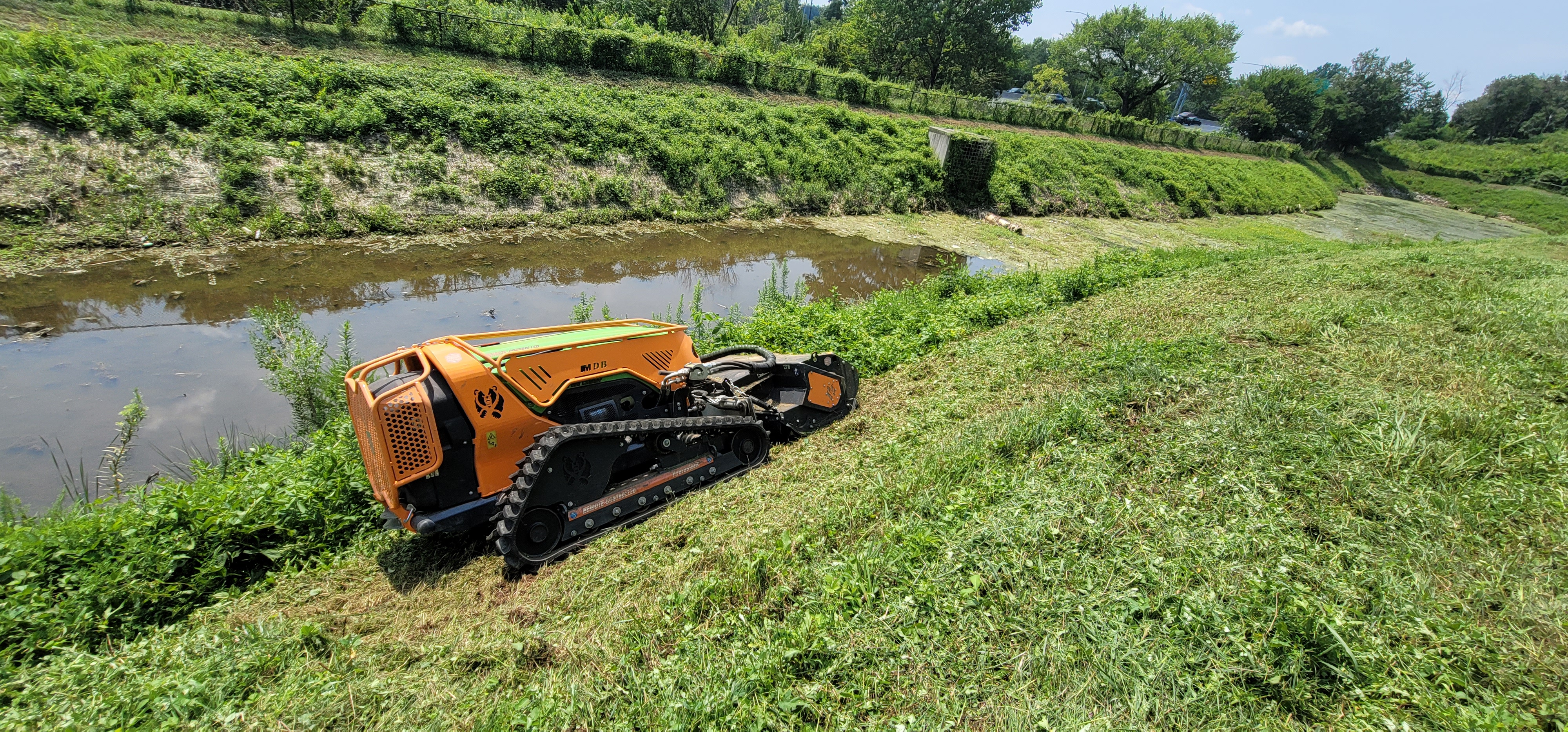 Stormwater maintenance crew mowing overgrown vegetation stormwater control measures