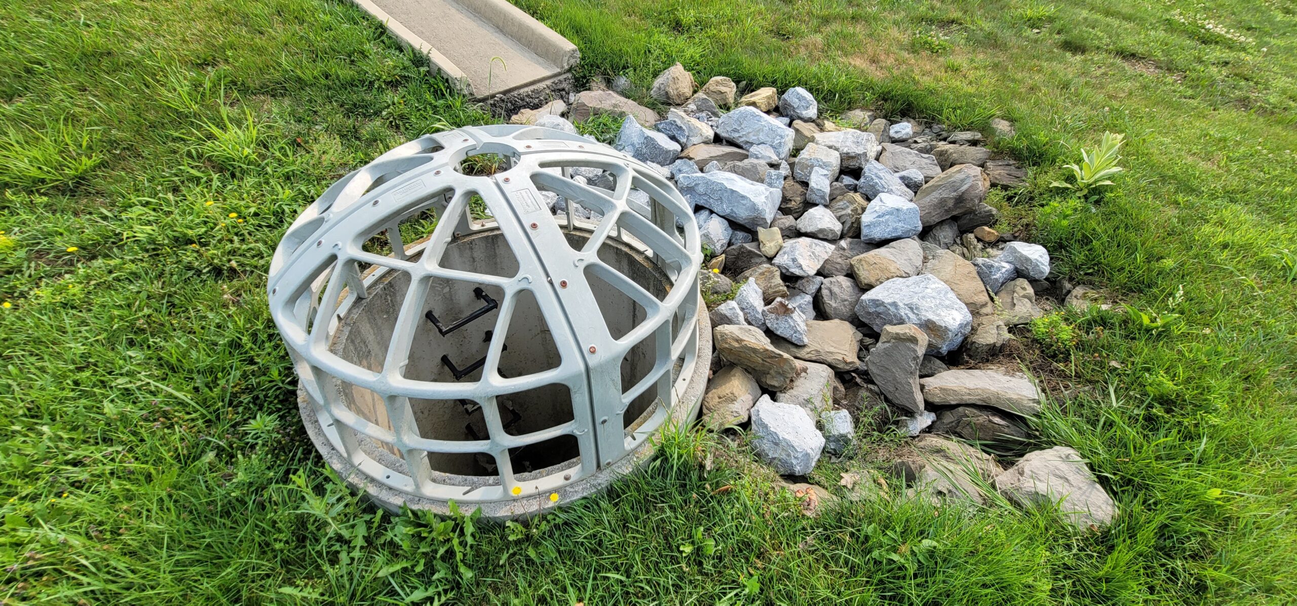 Stormwater SCM outlet structure with orifice, riser, and trash rack requiring inspection and maintenance.