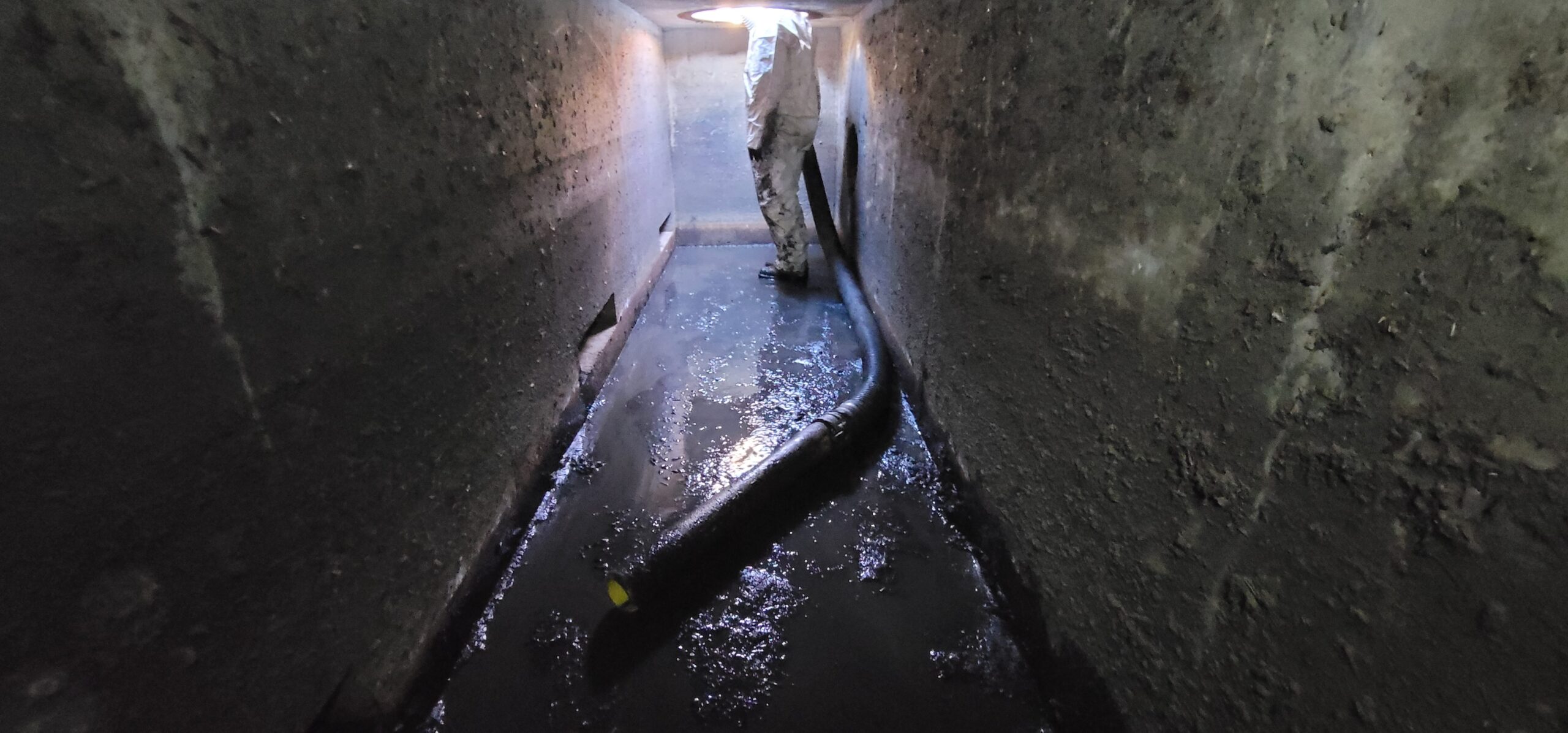 Technician performing maintenance on an underground stormwater control measure (SCM) vault, removing sediment and debris.