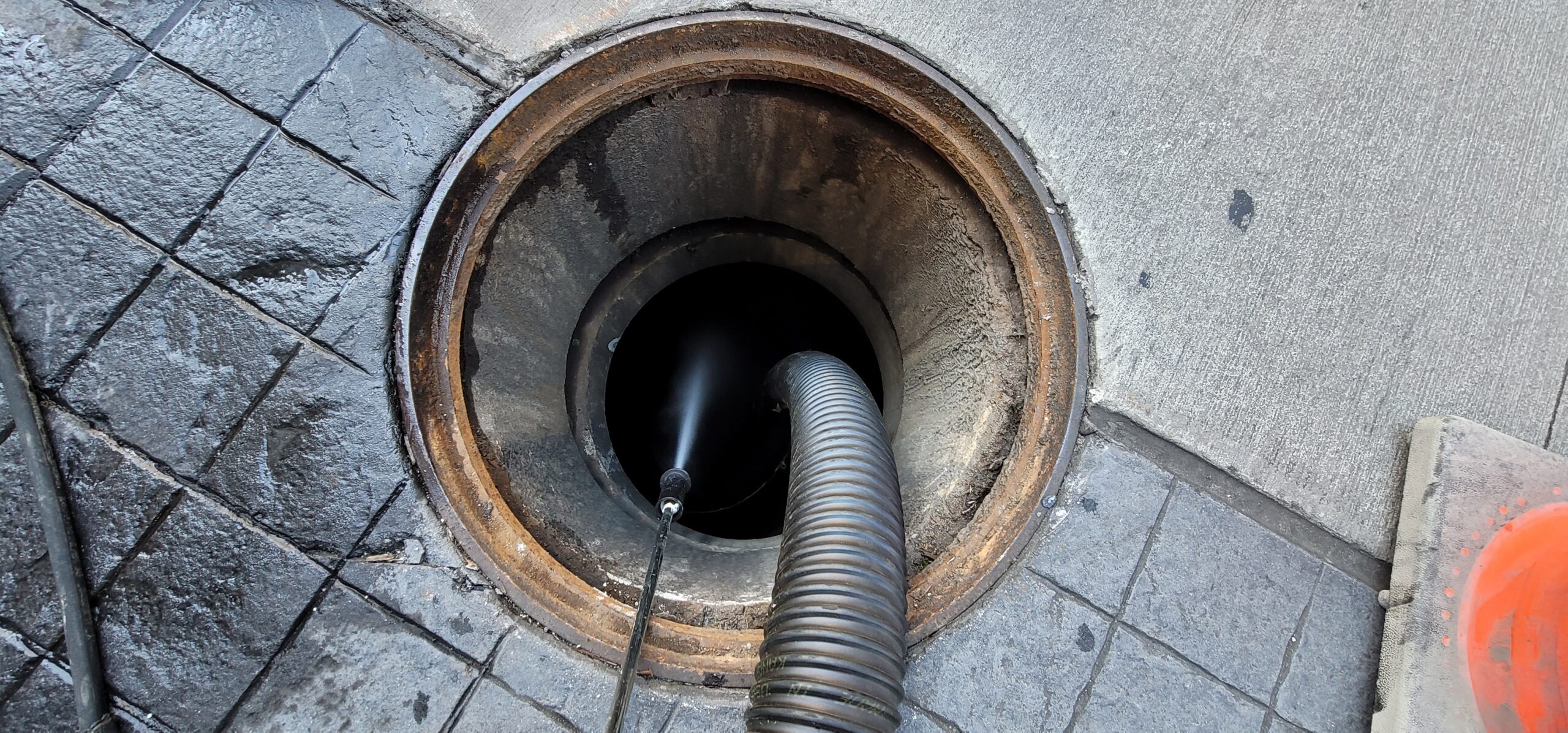Vactor truck performing industrial cleaning, including sand and oil interceptor maintenance.