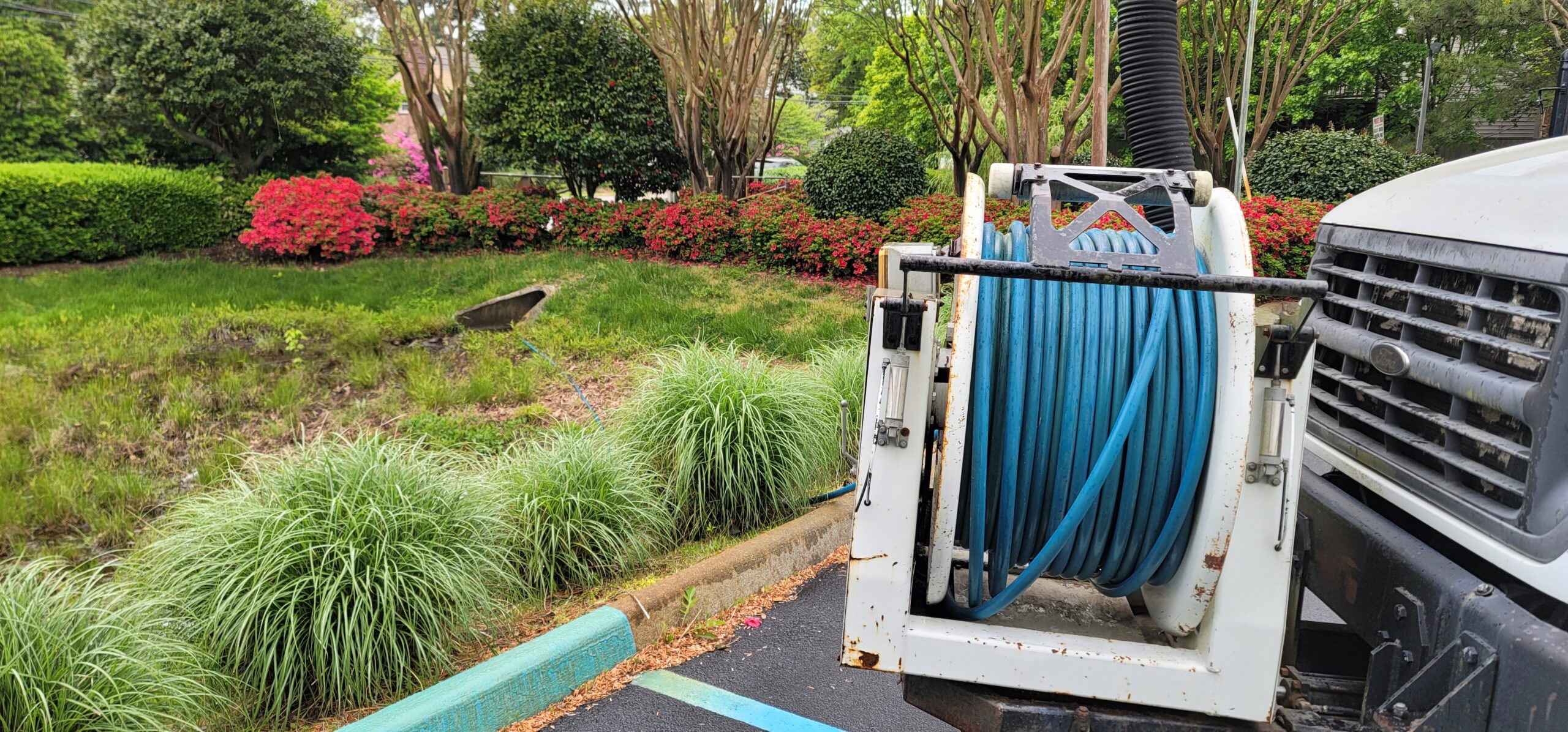 Vactor truck vacuum removing sediment from retention or detention pond to restore capacity.