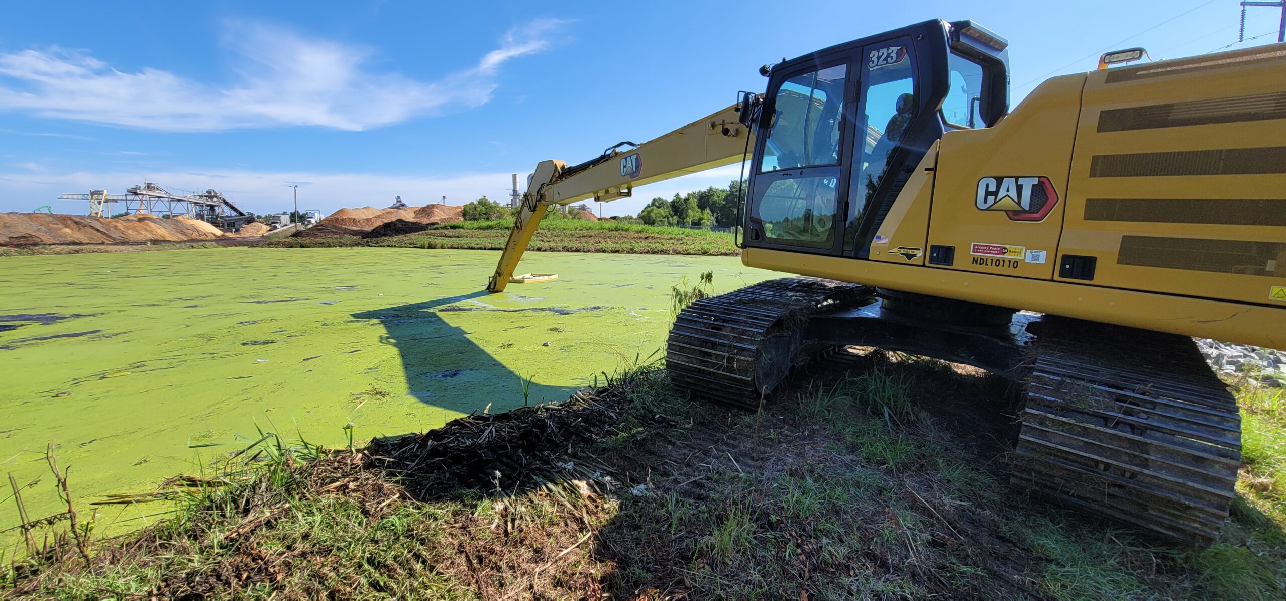 Mechanical dredging of stormwater retention pond removing accumulated sediment to restore detention basin capacity
