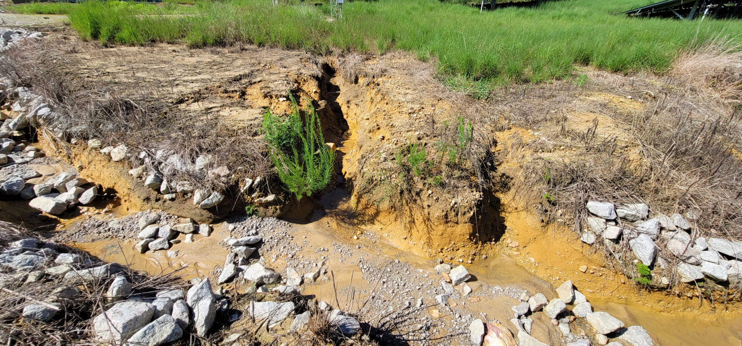 Severe embankment erosion near stormwater inlet compromising structural stability