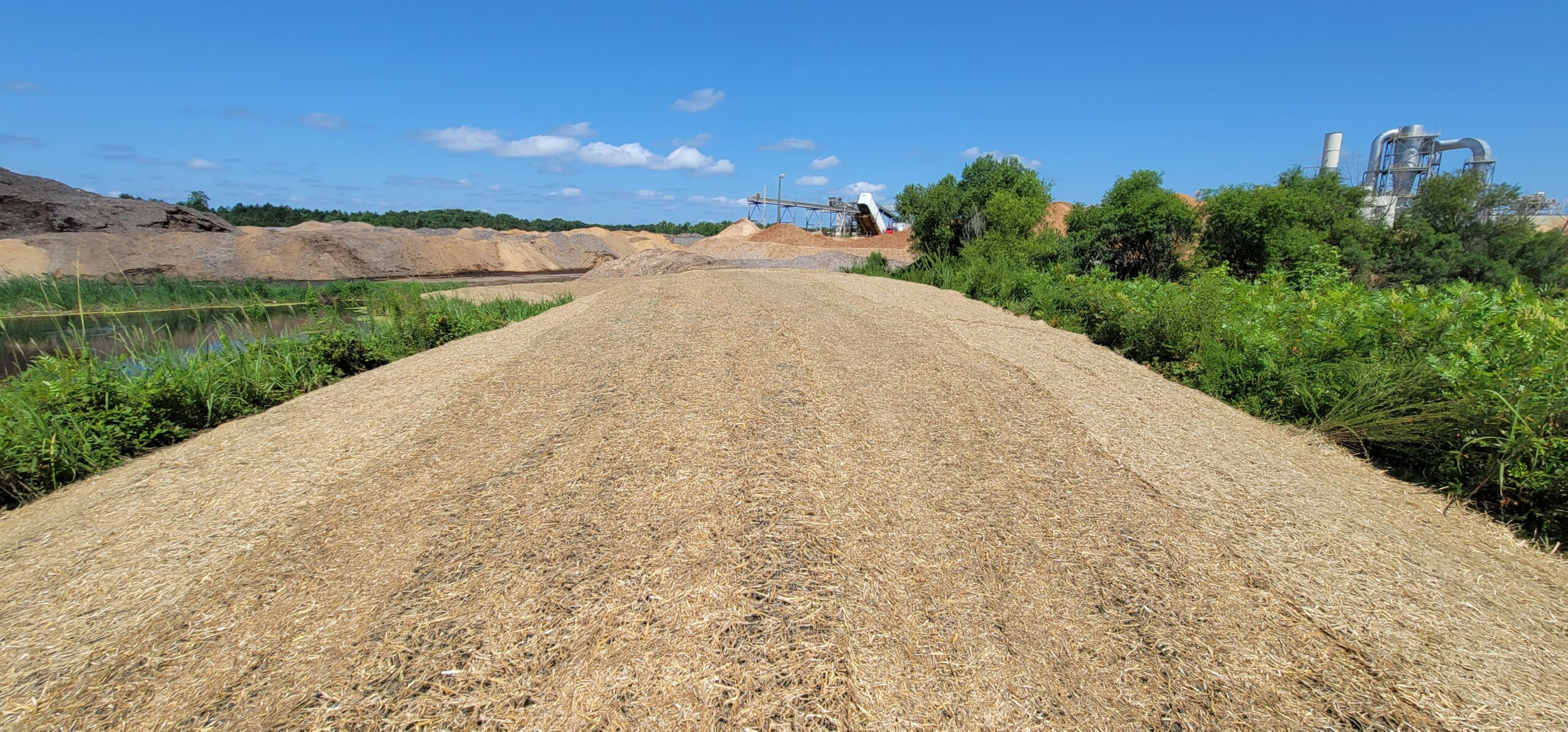 Stabilized detention pond embankment with sod, riprap, and erosion control matting to prevent soil loss and sedimentation.