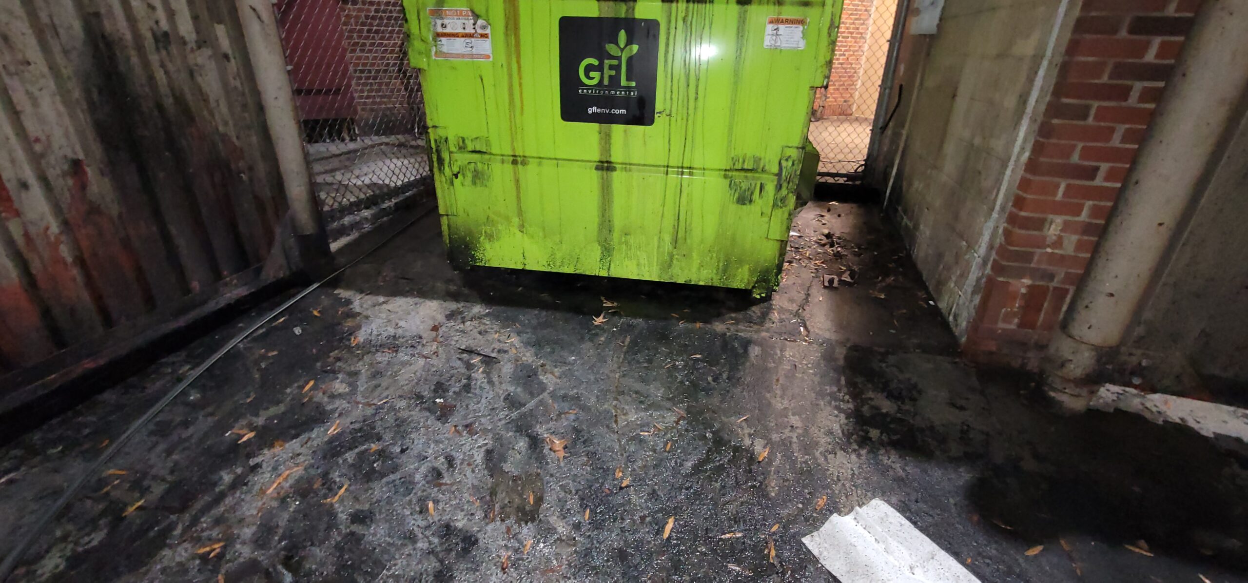 Stormwater inspector checking for oil sheen, chemical discharge, and illegal dumping in a municipal drainage system.