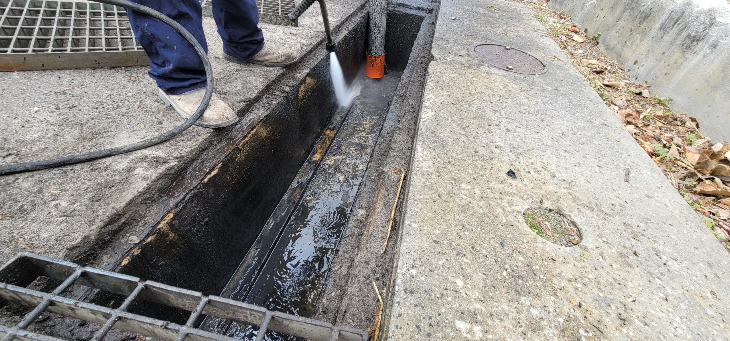Vacuum truck removing sediment and debris from storm drain catch basin to prevent flooding.