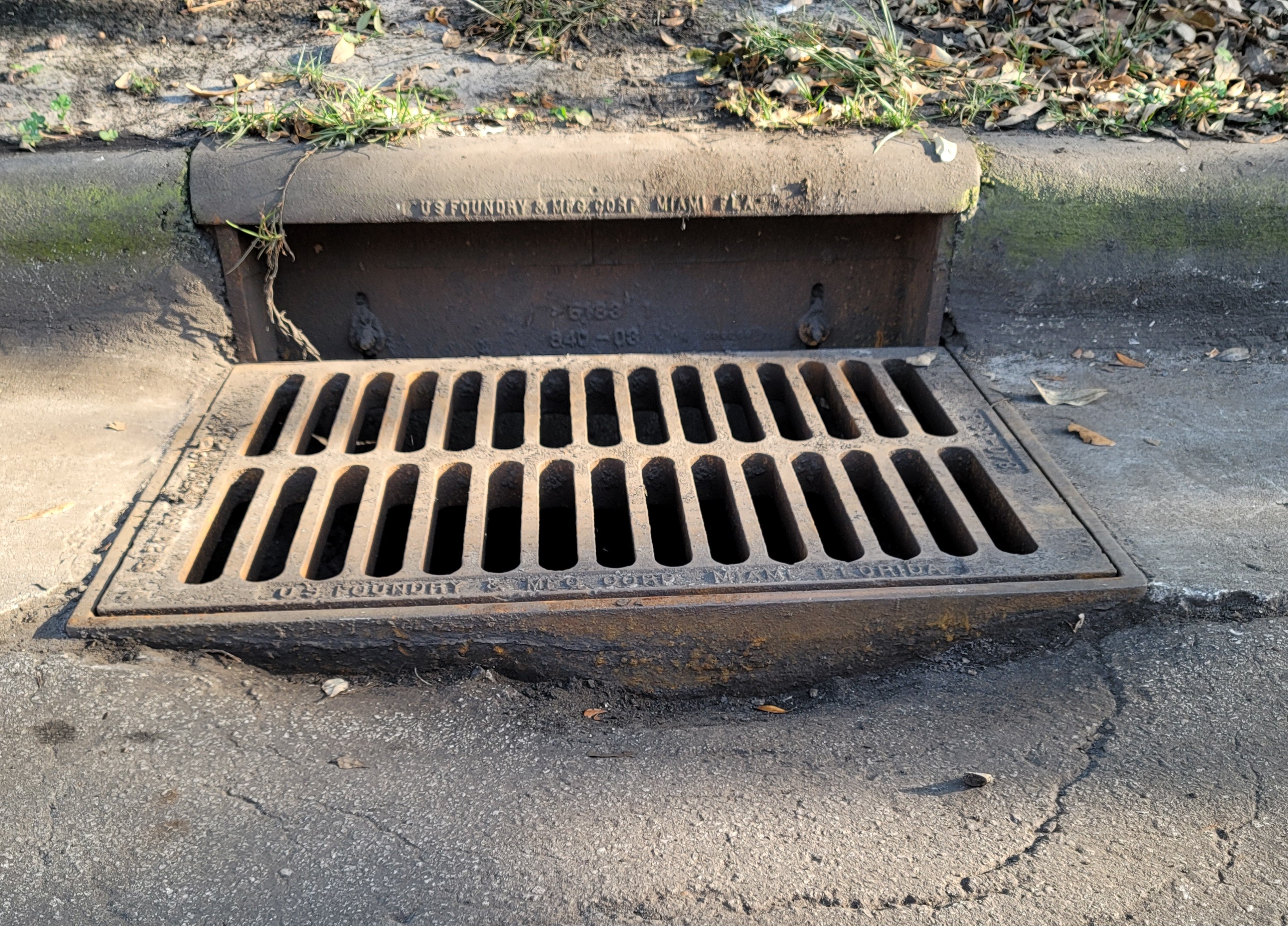 Stormwater catch basin surrounded by a developing sinkhole with repair crew stabilizing the area.